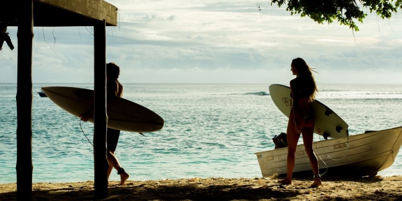 Two surfers walking toward the ocean with their boards, ready to surf